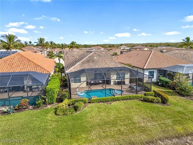 view of pool with glass enclosure, a lawn, and a patio area