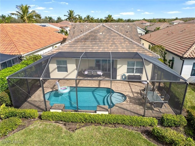 rear view of house with glass enclosure, a patio area, and a swimming pool with hot tub