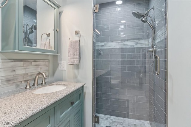 bathroom featuring tiled shower, vanity, and tasteful backsplash