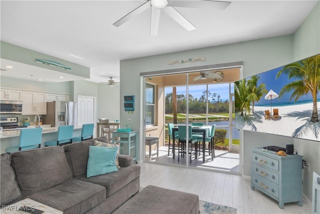 living room with sink, light hardwood / wood-style floors, and ceiling fan