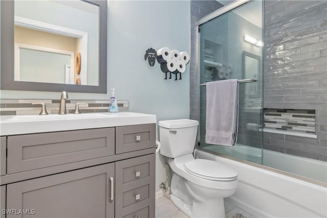 full bathroom with bath / shower combo with glass door, toilet, and vanity