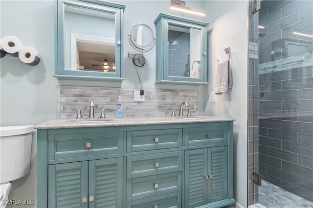 bathroom featuring toilet, decorative backsplash, a shower with shower door, and vanity