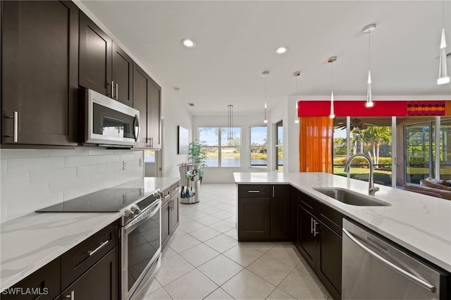 kitchen with sink, appliances with stainless steel finishes, tasteful backsplash, light tile patterned flooring, and decorative light fixtures