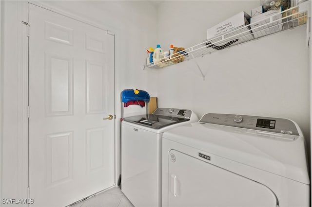 clothes washing area with light tile patterned flooring and washer and dryer