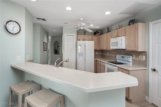 kitchen with tasteful backsplash, kitchen peninsula, a kitchen breakfast bar, and white appliances