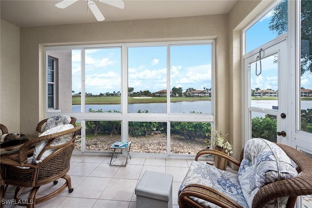 sunroom featuring ceiling fan, a water view, and a healthy amount of sunlight