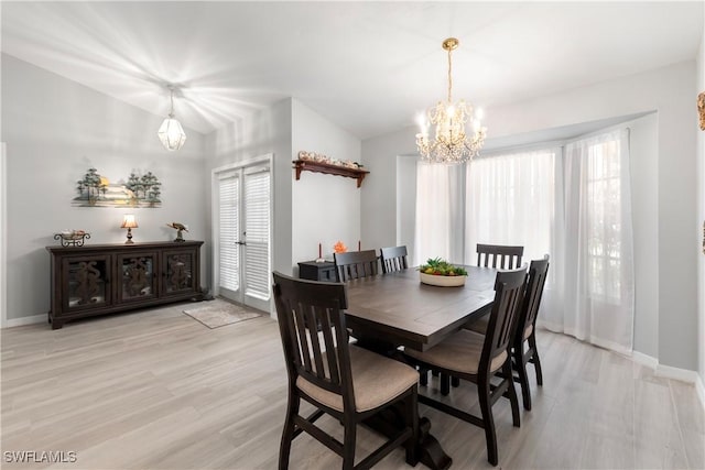 dining space with light hardwood / wood-style floors, vaulted ceiling, and an inviting chandelier