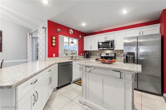 kitchen with stainless steel appliances, white cabinetry, kitchen peninsula, and a kitchen island