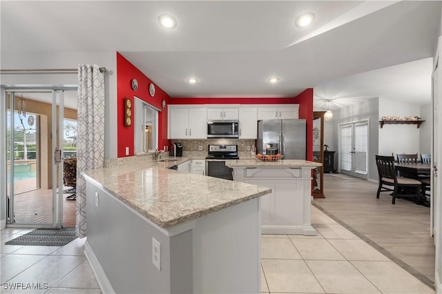 kitchen featuring white cabinets, stainless steel appliances, kitchen peninsula, and plenty of natural light