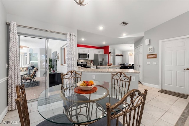 dining area with an inviting chandelier, light tile patterned floors, and lofted ceiling