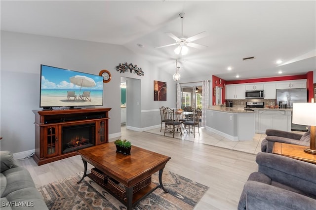 living room featuring ceiling fan, light wood-type flooring, and vaulted ceiling