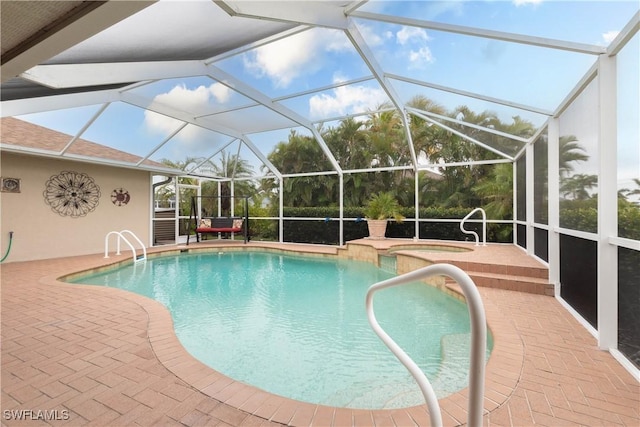 view of swimming pool with glass enclosure, a patio area, and a hot tub