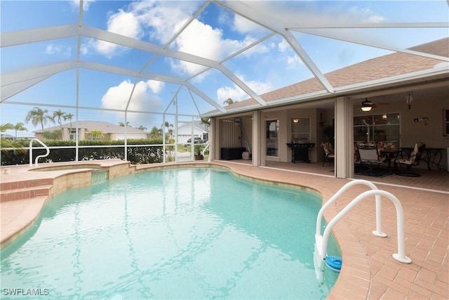 view of pool featuring a patio, an in ground hot tub, glass enclosure, and ceiling fan