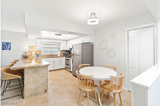 kitchen with sink, a breakfast bar area, kitchen peninsula, stainless steel appliances, and white cabinets