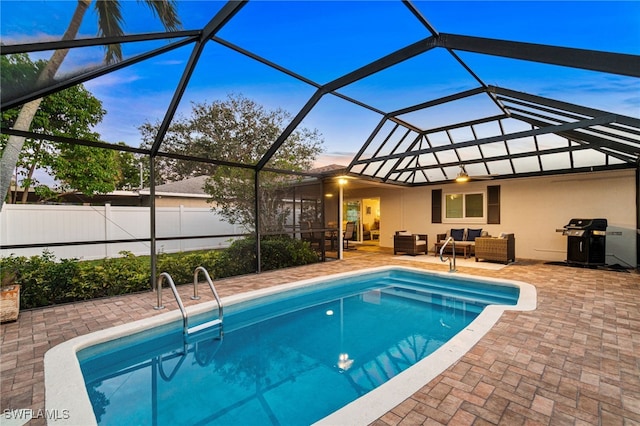 pool at dusk featuring a lanai, an outdoor hangout area, and a patio area