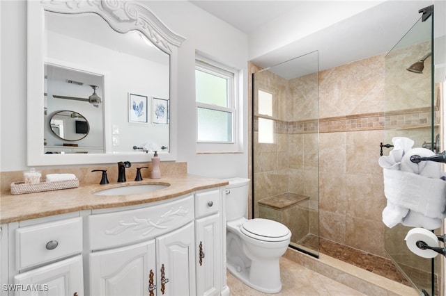 bathroom with tile patterned flooring, vanity, a tile shower, and toilet