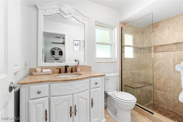 bathroom with tiled shower, vanity, and toilet