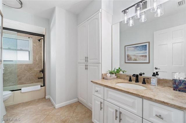 full bathroom with tile patterned flooring, bath / shower combo with glass door, vanity, and toilet