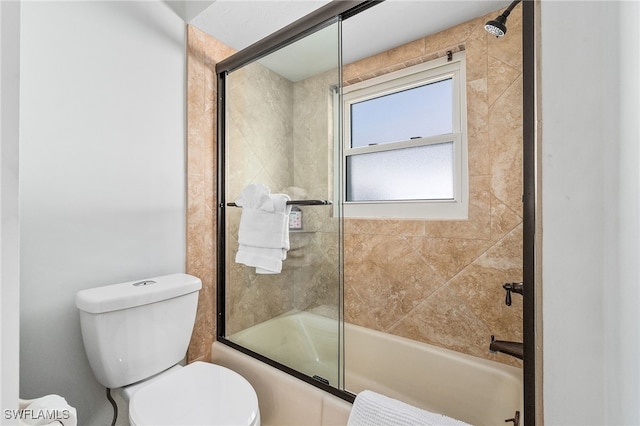 bathroom featuring toilet and combined bath / shower with glass door