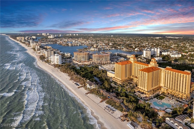 aerial view at dusk with a beach view and a water view