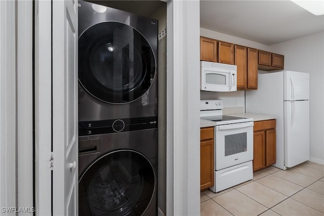 kitchen with light tile patterned floors, white appliances, and stacked washing maching and dryer