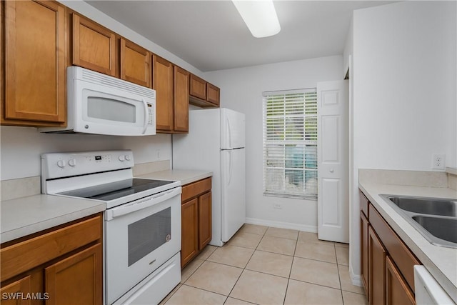 kitchen with white appliances, sink, and light tile patterned floors