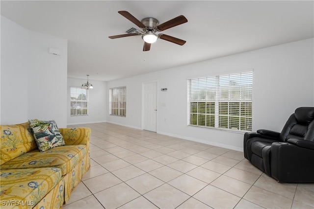 tiled living room with ceiling fan with notable chandelier and a wealth of natural light