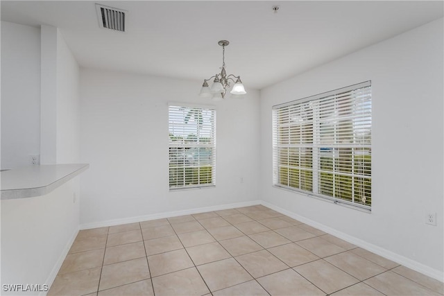 unfurnished dining area with light tile patterned floors and a notable chandelier