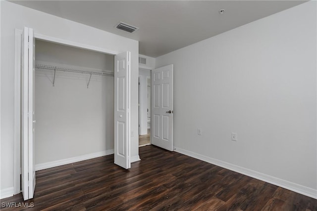 unfurnished bedroom featuring dark hardwood / wood-style flooring and a closet