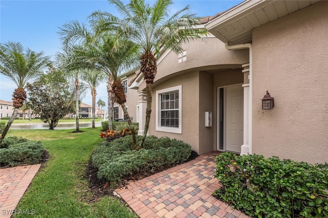 property entrance featuring a yard and stucco siding