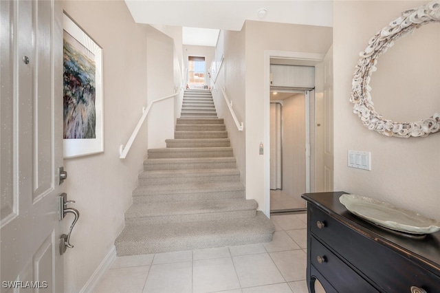 stairs with elevator, tile patterned flooring, and baseboards