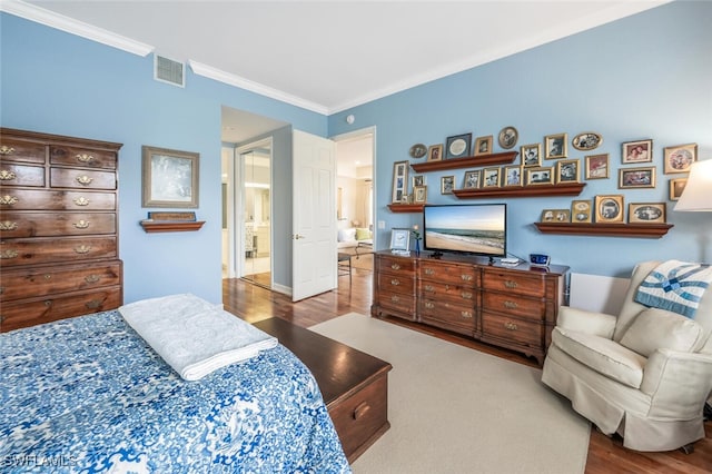 bedroom featuring connected bathroom, hardwood / wood-style flooring, and ornamental molding