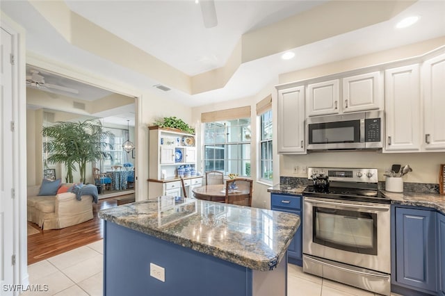 kitchen with appliances with stainless steel finishes, white cabinets, a center island, ceiling fan, and blue cabinetry