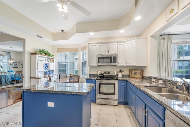 kitchen with sink, appliances with stainless steel finishes, a center island, white cabinets, and blue cabinets