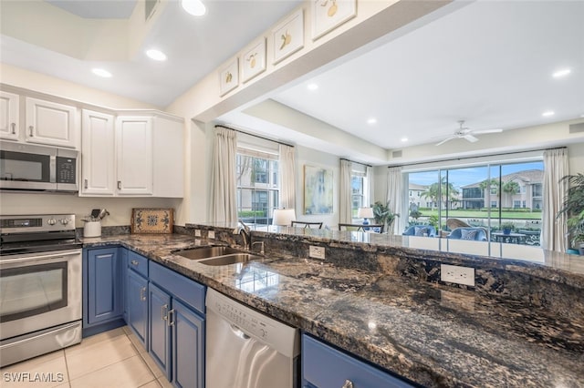 kitchen with sink, stainless steel appliances, white cabinets, and blue cabinets