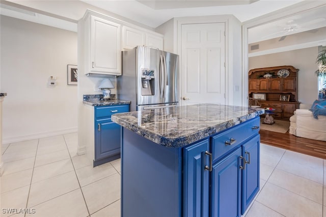 kitchen featuring white cabinetry, stainless steel fridge, a center island, and blue cabinetry