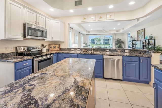 kitchen featuring white cabinetry, sink, dark stone countertops, stainless steel appliances, and blue cabinetry