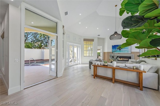 living room featuring lofted ceiling, french doors, and light hardwood / wood-style flooring