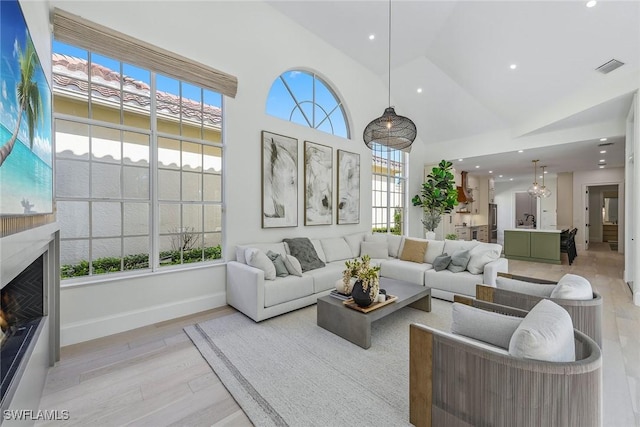 living room with high vaulted ceiling, light wood-type flooring, and sink