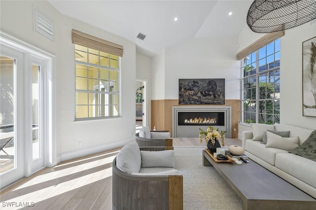 living room featuring a healthy amount of sunlight, light hardwood / wood-style floors, and high vaulted ceiling