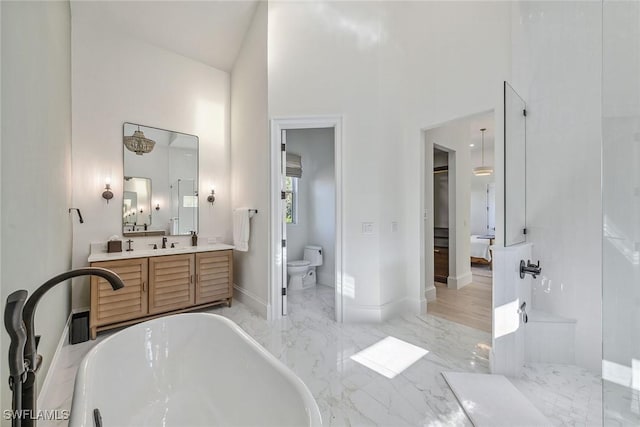 bathroom featuring toilet, a tub to relax in, vanity, and a towering ceiling