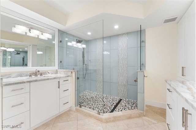 bathroom featuring a shower with shower door, vanity, and tile patterned floors