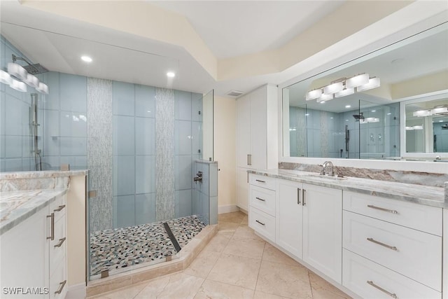 bathroom featuring a shower with shower door and vanity