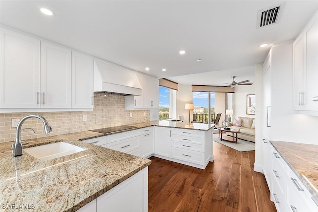 kitchen featuring white cabinetry, sink, kitchen peninsula, light stone counters, and black electric cooktop