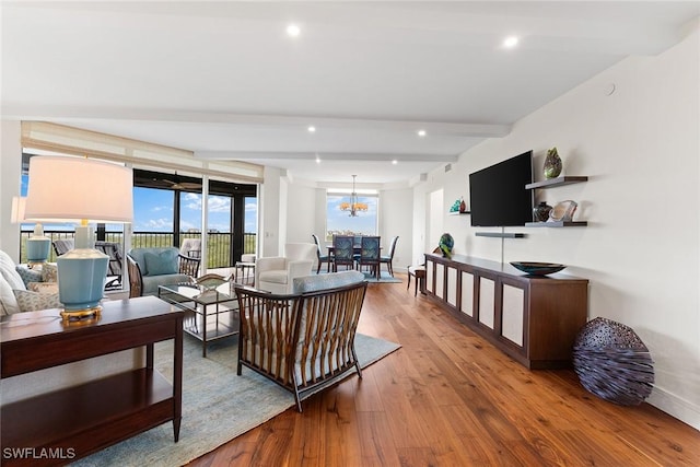 living room with hardwood / wood-style flooring, beamed ceiling, and an inviting chandelier