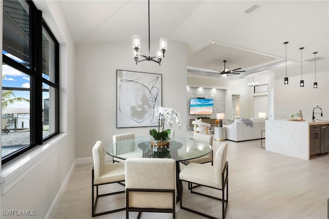 dining area with sink, light hardwood / wood-style floors, and ceiling fan with notable chandelier