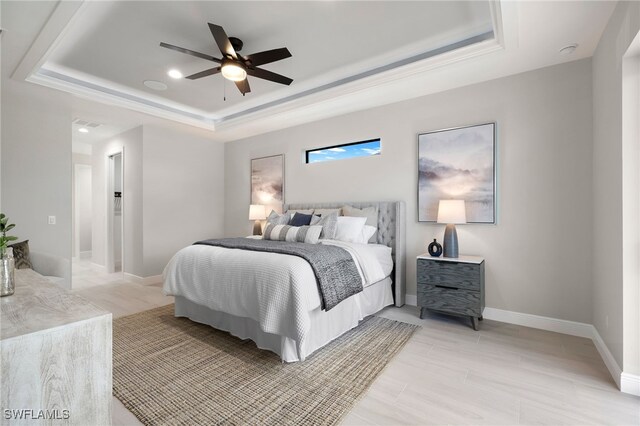 bedroom with ceiling fan and a tray ceiling