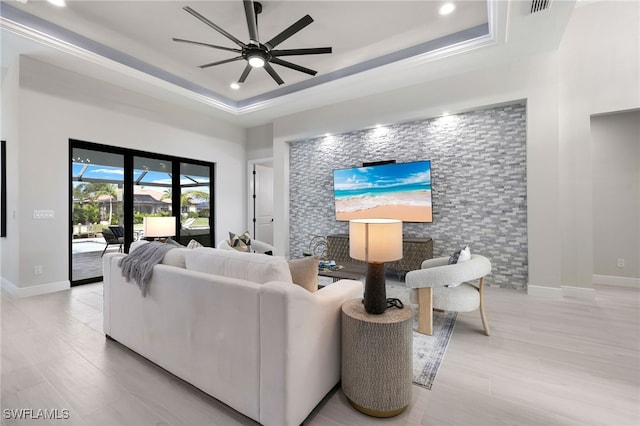 living room with ceiling fan and a raised ceiling