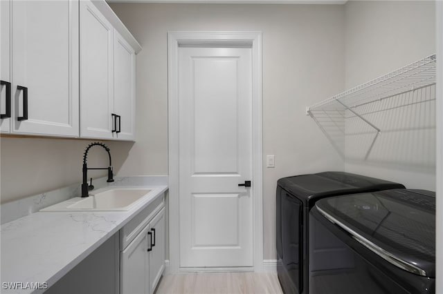 laundry area with sink, separate washer and dryer, and cabinets