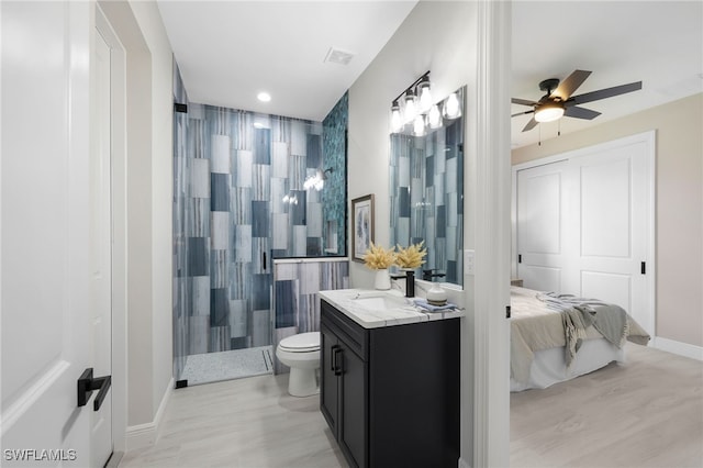 bathroom featuring ceiling fan, vanity, a tile shower, and toilet